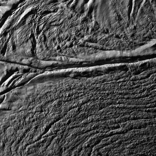 Rów tektoniczny na Enceladusie, z którego emitowane są cząstki pary wodnej; fotografia z pokładu sondy Cassino / Zdjęcie: NASA