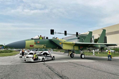 Samolot F-15EX w żółto-zielonych barwach farb podkładowych przekracza ulicę oddzielającą halę montażową od lotniska. Widać, że samolot nie ma jeszcze pełnego wyposażenia kabiny załogi i jej owiewki / Zdjęcie: Boeing