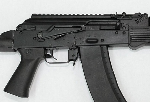 Komora zamkowa zmodernizowanego AK-74. Zwraca uwagę nowa pokrywa zintegrowana z uniwersalną szyną montażową, na wzór zastosowanej w AK-12. Ciekawe jest umieszczenie zatrzasku pokrywy, nie w tylnej części, ale z prawej strony z boku. Dobrze widoczny nowy, ergonomiczny chwyt pistoletowy, zdublowana dźwignia bezpiecznika/przełącznika rodzaju ognia (obok języka spustowego), jak też dodatkowa półeczka pod palec w standardowym skrzydełku AK / Zdjęcie: Iżmasz