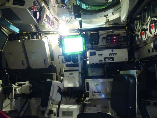 Centralnie położony komputer dowódcy (terminal WB Electronics DD9620T), nieco niżej – na wysokości oparcia fotela, biała skrzynia komputera sterowania wieżą